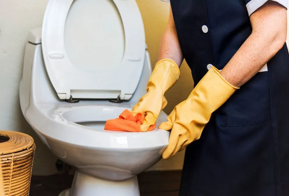 Persoon die een toilet schoonmaakt.