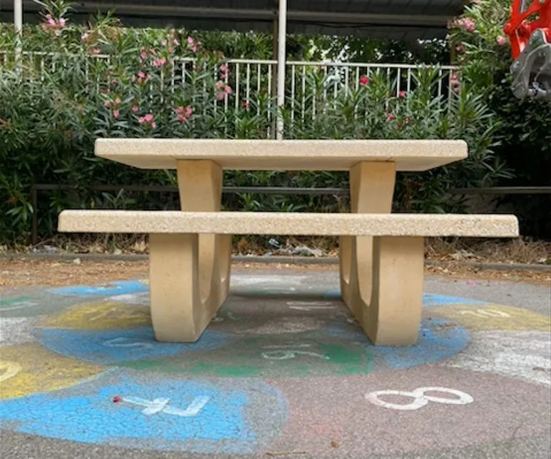 Table de jeux en béton blanc avec deux damiers intégrés devant un bâtiment public