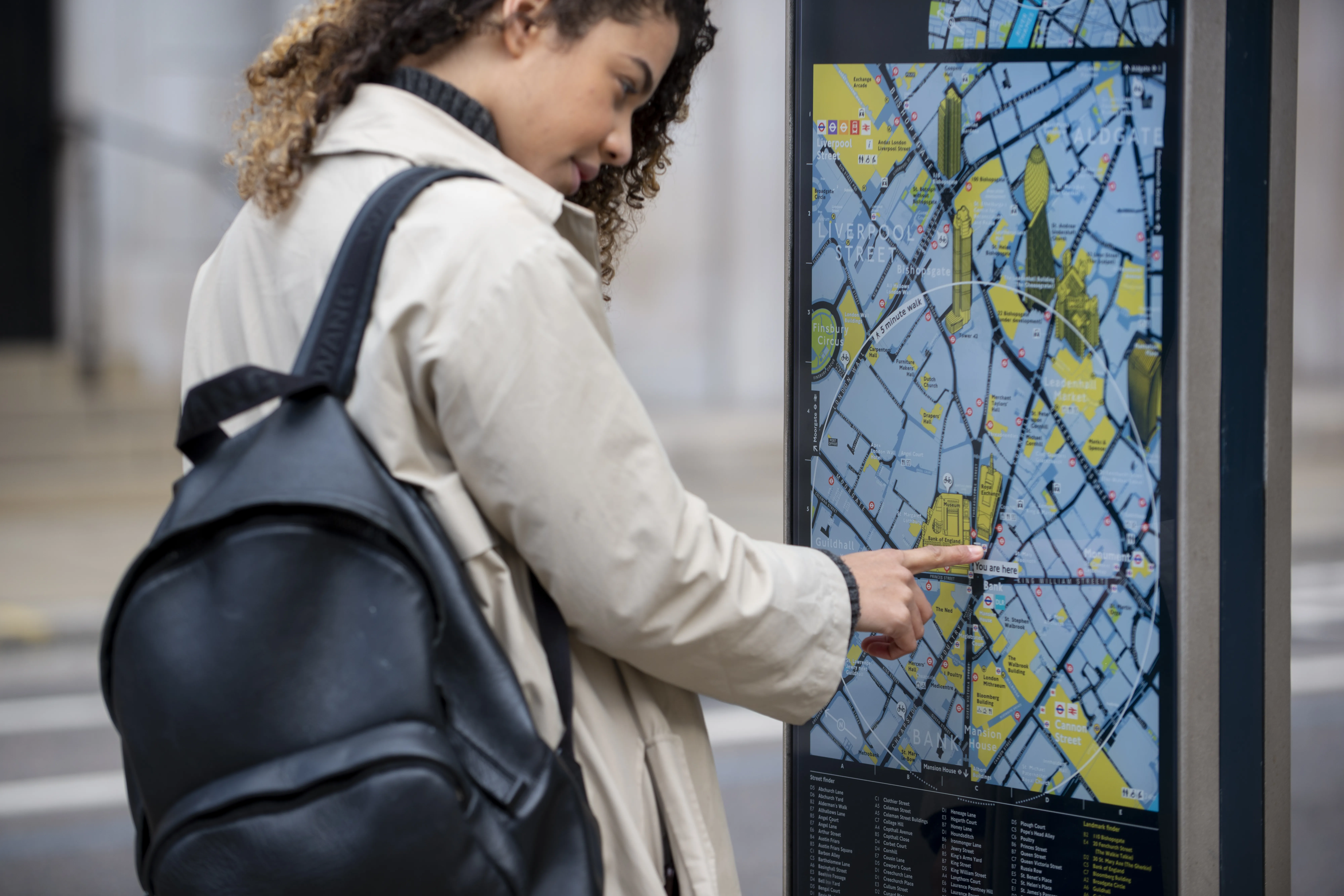 Jeune femme consultant un plan sur un panneau d’information urbain