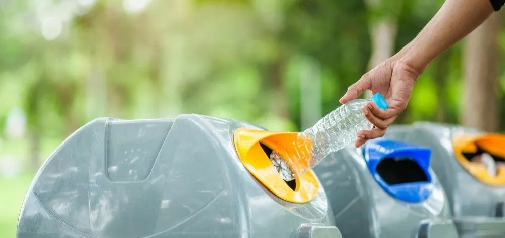 personne qui jette une bouteille dans une poubelle