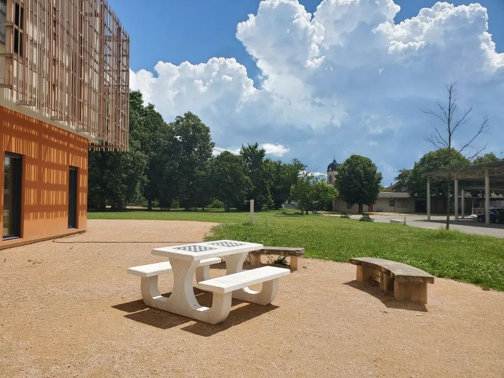 Table de jeux extérieure en béton avec assises intégrées installée dans une cour d'école